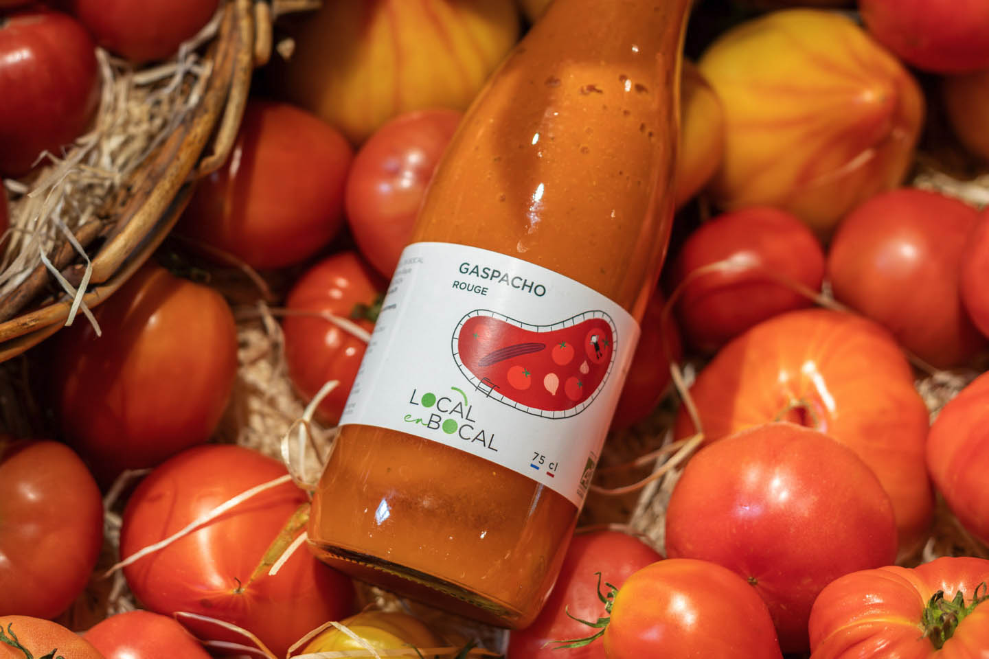 Bouteille de gaspacho rouge Local en Bocal entourée de tomates